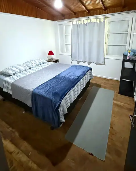 Quarto com cama de casal, abajur e janela com cortina