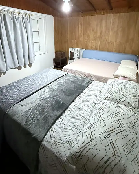Quarto com duas camas e parede de madeira